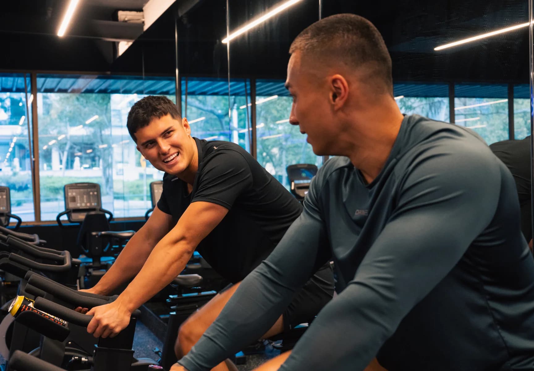 Friends working out together on exercise bikes at Housed Sydney